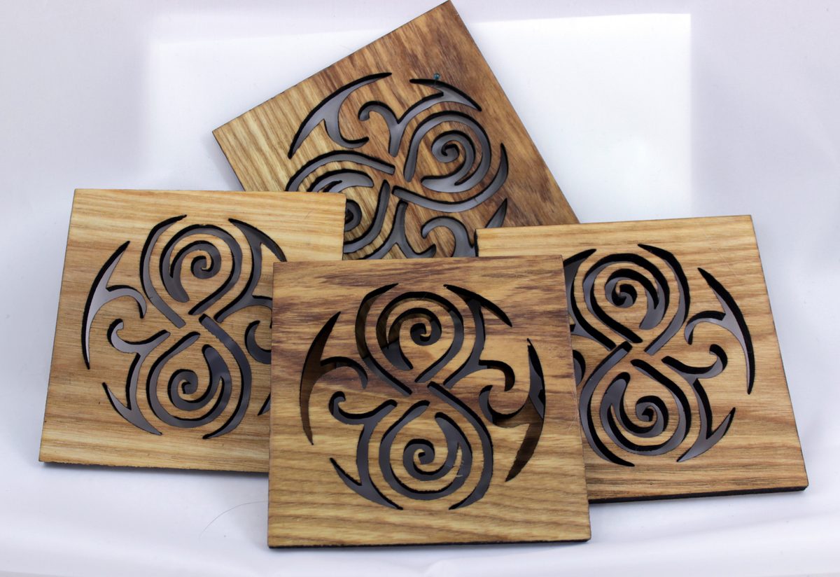 Four laser-cut wooden coasters with circular spiral designs